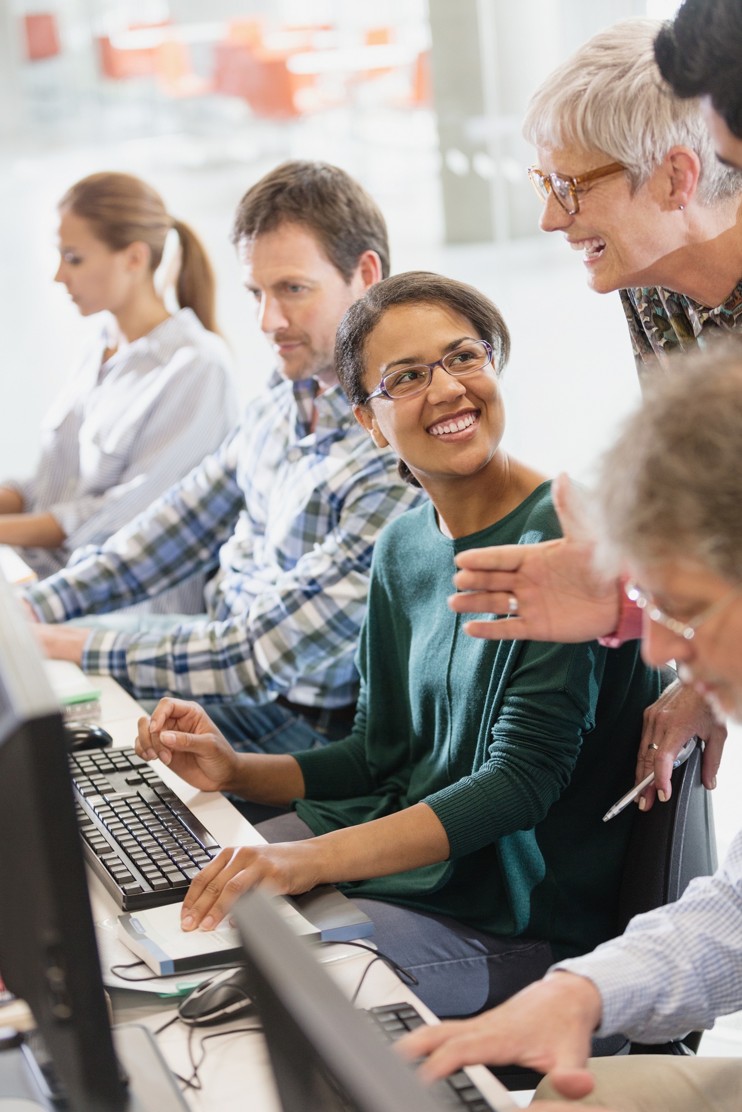 Students talking at computers in adult education classroom